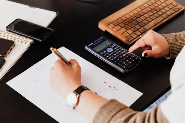 crop-woman-using-calculator-and-taking-notes-on-paper